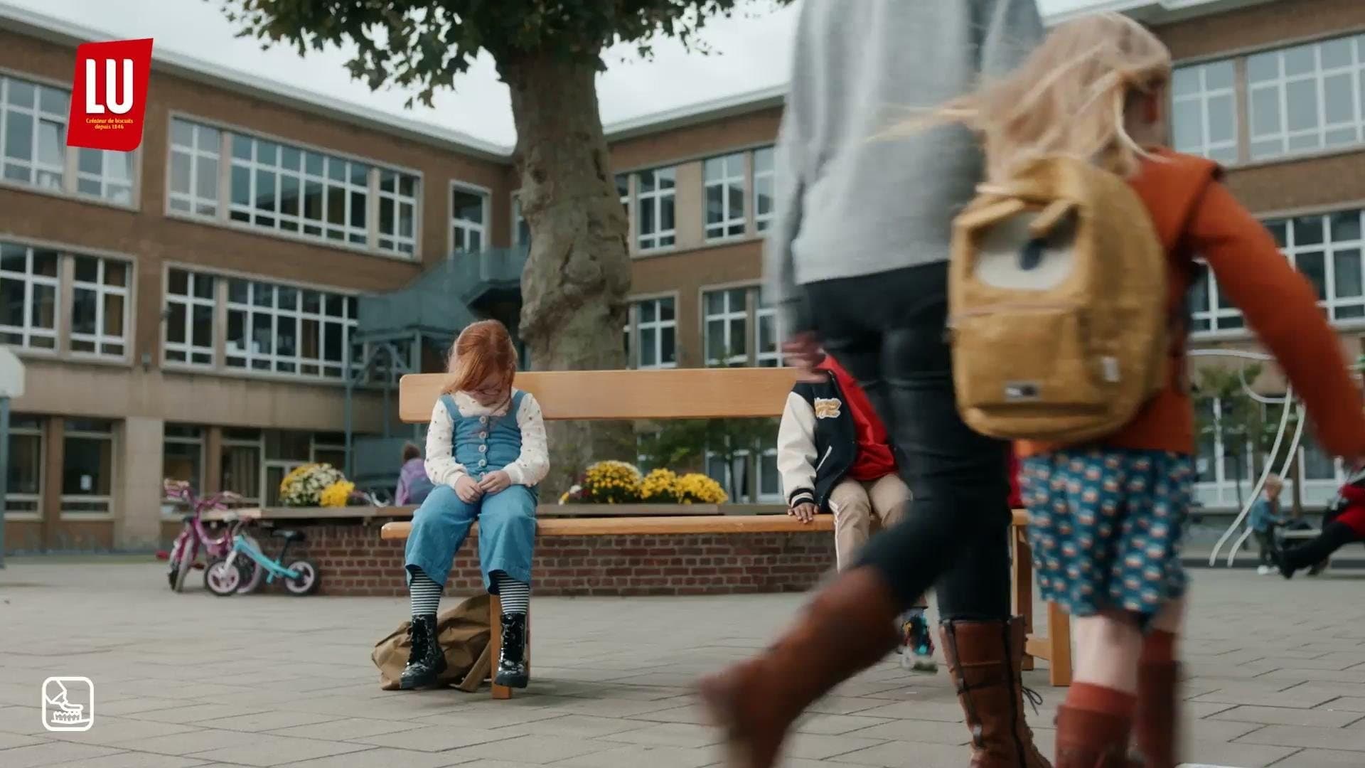 Still from the LU TV commercial: a girl alone on a school bench while classmates walk past